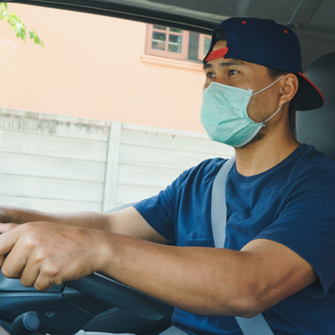hispanic man driving a truck with a mask on